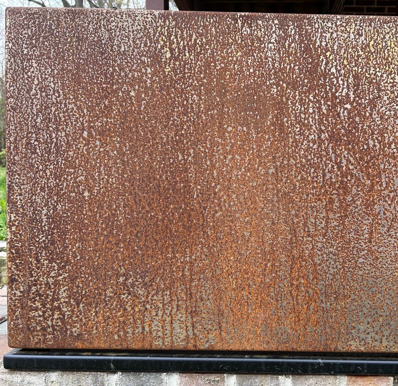 rust covered metal planter with black drip tray